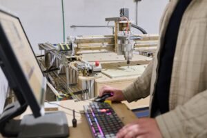 Operator Entering Coordinates on Computer for CNC Machine to Precisely Cut Wooden Pieces